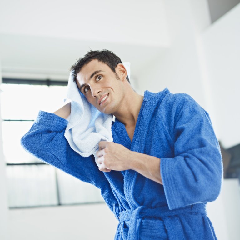 man in bathrobe dries hair with towel